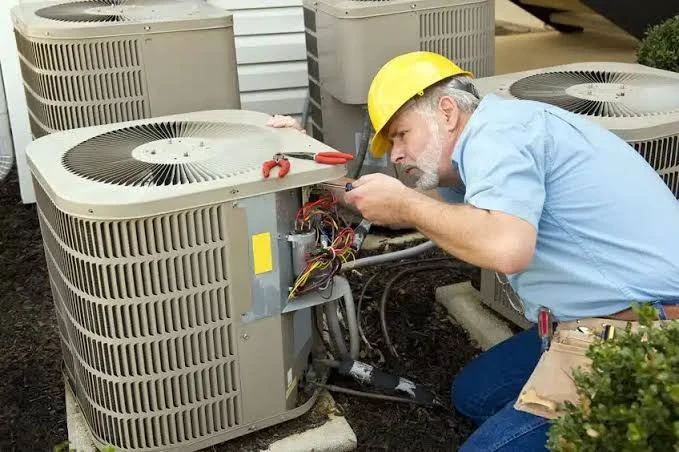 HVAC service professional inspecting outdoor condenser wiring