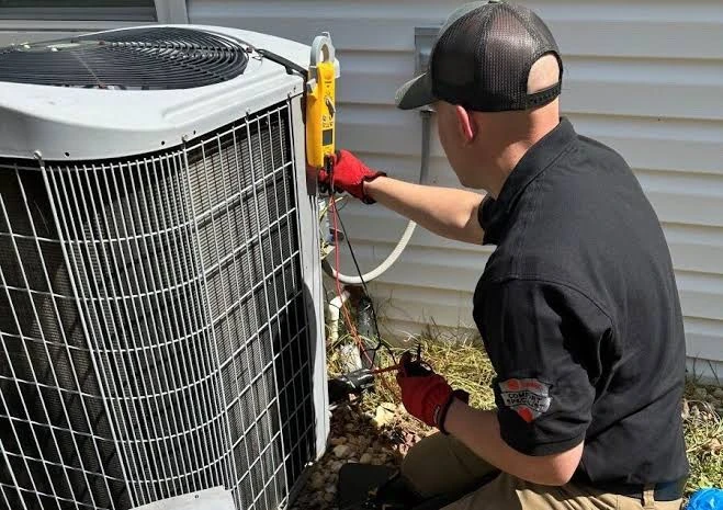HVAC service professional measuring electrical performance at an outdoor unit