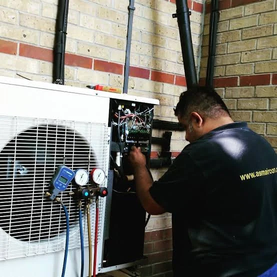 HVAC service professional checking outdoor equipment with diagnostic gauges
