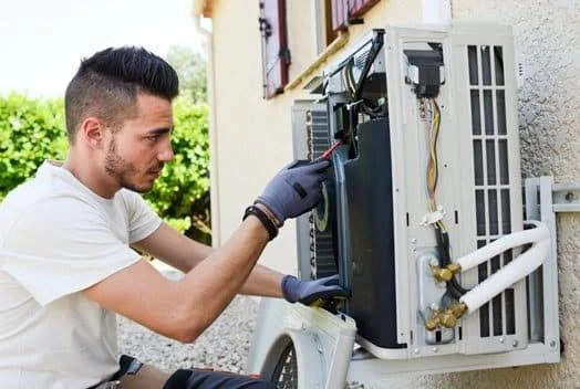 HVAC service professional examining an opened outdoor heat pump unit