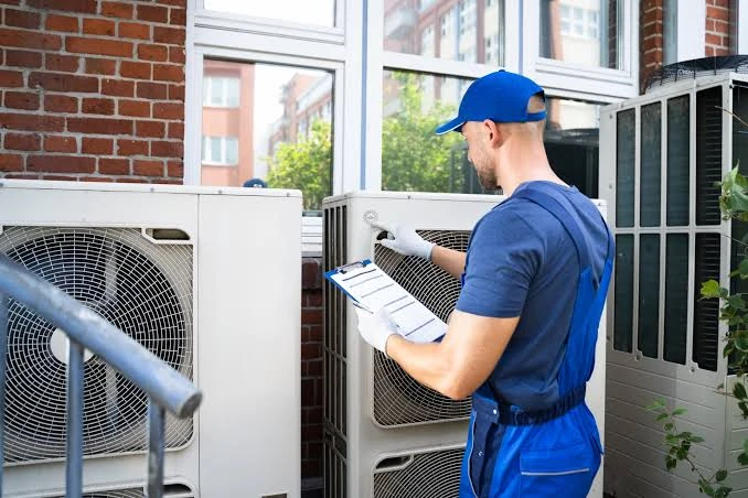 HVAC service professional inspecting outdoor units with a clipboard